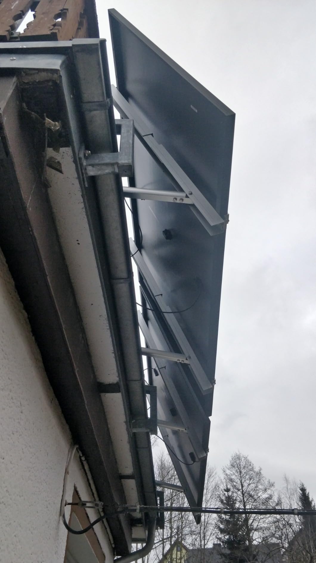 Zwei Solarmodule mit Metallhalterung an einer verputzten Hauswand verschraubt