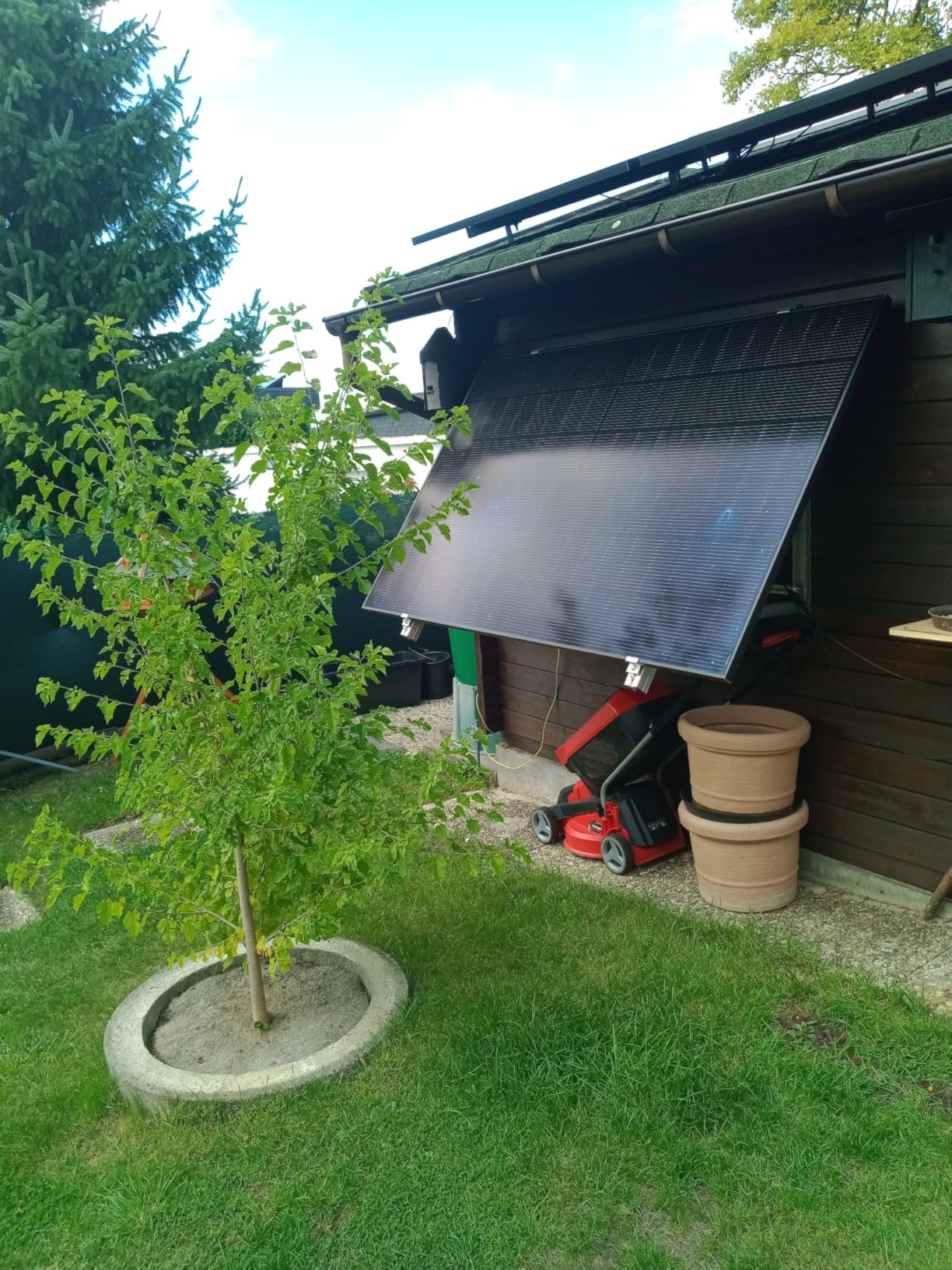 Balkonkraftwerk mit Wandhalterung am Gartenhaus, Modul angewinkelt nach vorn im Garten